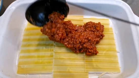 Se añade el relleno de salsa ragù sobre las láminas de pasta - La mesa del Conde