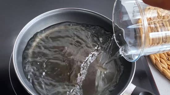 Añadir el agua en una sartén para calentarla - la mesa del Conde