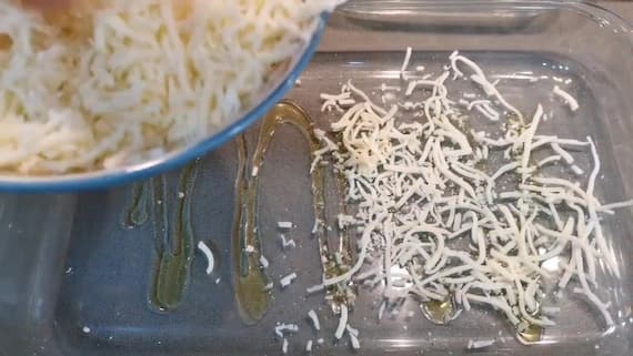A la base de una bandeja, se añade aceite de oliva virgen extra y queso rallado - La mesa del Conde